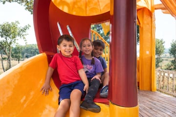 young students sliding down a playground slide