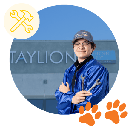 Smiling student in a blue graduation gown holding wrenches in front of the Taylion school building, with a yellow icon of tools and two orange paw prints, inside a blue-toned circular background.