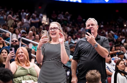 Parents holding their phones and cheering for students